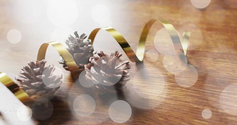 Festive pinecones with golden ribbon on wooden surface
