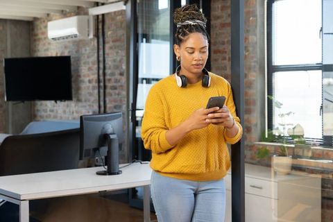 Young professional using smartphone in modern industrial office with headphones