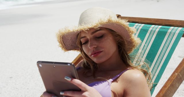 Young woman relaxing on beach sunbed reading tablet - Download Free Stock Images Pikwizard.com