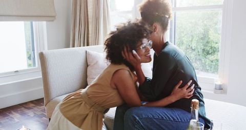 Same-Sex Female Couple Embracing on Couch in Home Setting