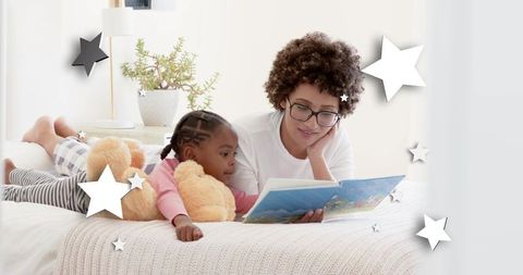 Caregiver reading bedtime story with child cuddling teddy on cozy white bed