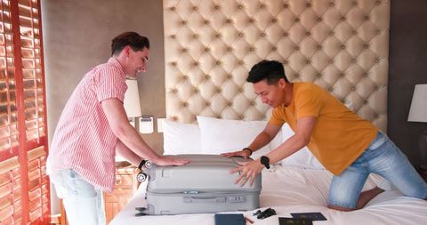 Excited Couple Packing Suitcase for Tropical Getaway