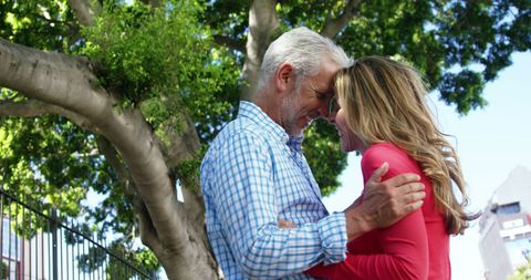 Mature Couple Embracing on Sunny Street with Greenery - Download Free Stock Images Pikwizard.com