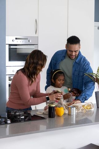 Family unpacking groceries at modern kitchen island using reusable mesh bags