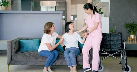 Senior Women with Nurse and Friends Enjoying Quality Time Together Indoors