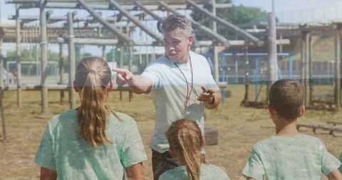 Coach instructing children at sports camp practicing athletics