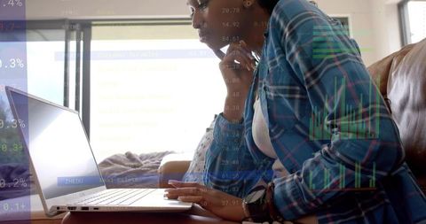 Remote worker analyzing financial charts on laptop at home, young woman telecommuting