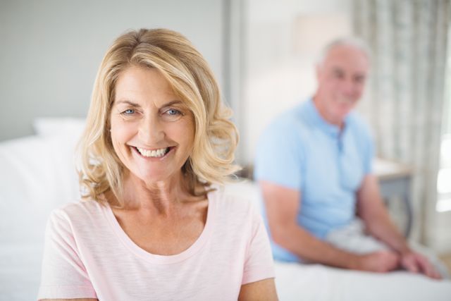 Senior Woman Smiling in Bedroom with Husband in Background - Download Free Stock Photos Pikwizard.com