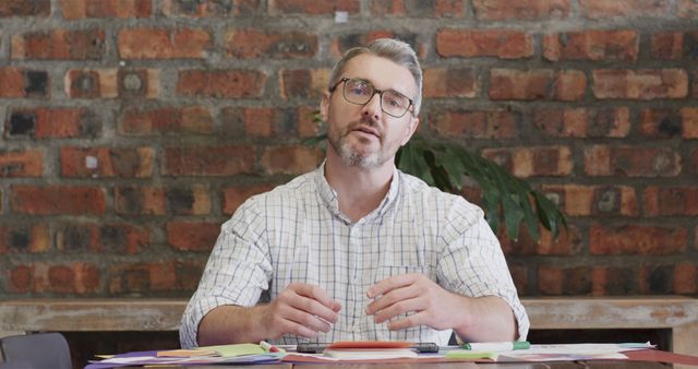 Businessman Working at Desk Against Brick Wall - Download Free Stock Images Pikwizard.com