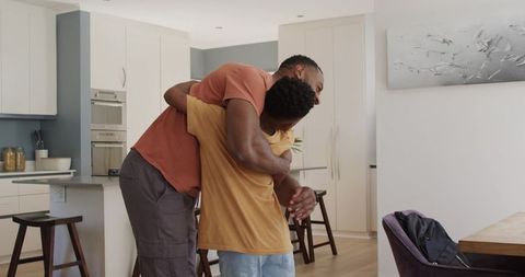 African american father hugging son in modern kitchen sharing warmth and family bond