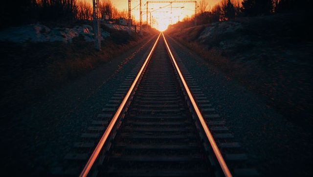 Sunset glow on railway tracks leading to distant horizon