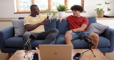 Diverse friends recording podcast on home sofa