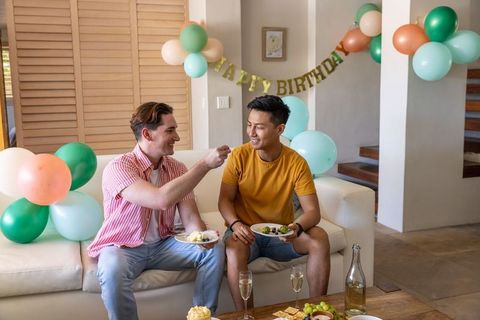 Multicultural friends sharing cupcake and champagne at intimate birthday party