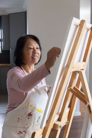 Senior Asian Woman Enjoying Painting at Home Easel