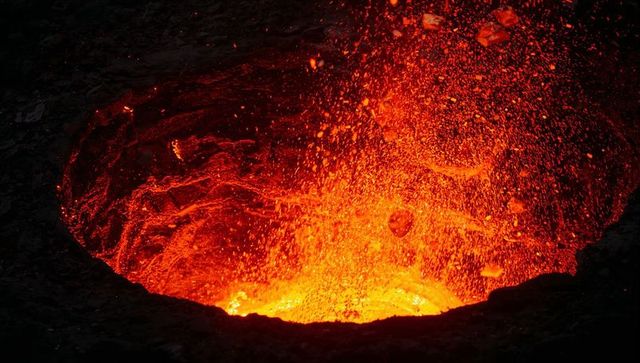 Volcanic lava erupting with fiery splashes in crater