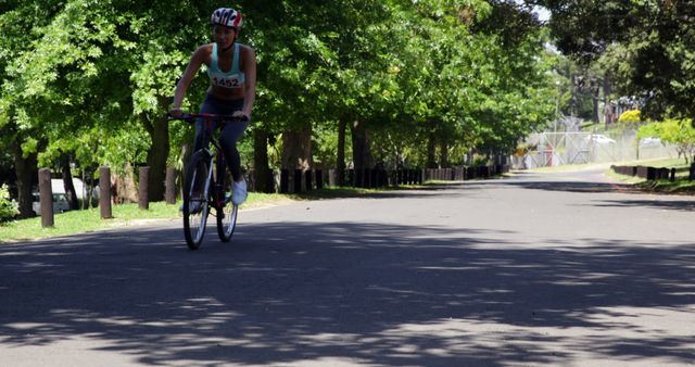 Female Cyclist Riding in Sunny Park with Bicycling Gear - Download Free Stock Images Pikwizard.com