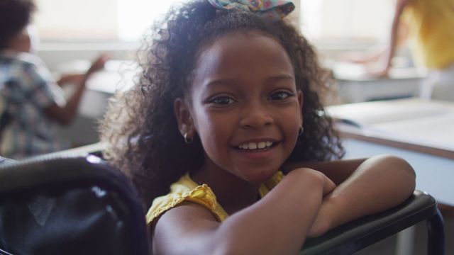 This video shows a happy African American girl sitting at a desk in a classroom, smiling brightly. She appears to be enthusiastic about learning, promoting positive education vibes. Ideal for educational websites, diversity and inclusion campaigns, and advertisements for school supplies.