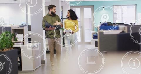 Coworkers walking and discussing strategy while collaborating in modern open-plan office
