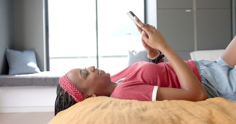 African American Woman Relaxing at Home Texting on Smartphone
