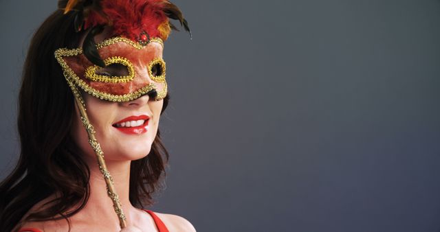 A Caucasian woman wears an ornate masquerade mask, with copy space. Her attire suggests a festive or carnival atmosphere, evoking mystery and celebration.