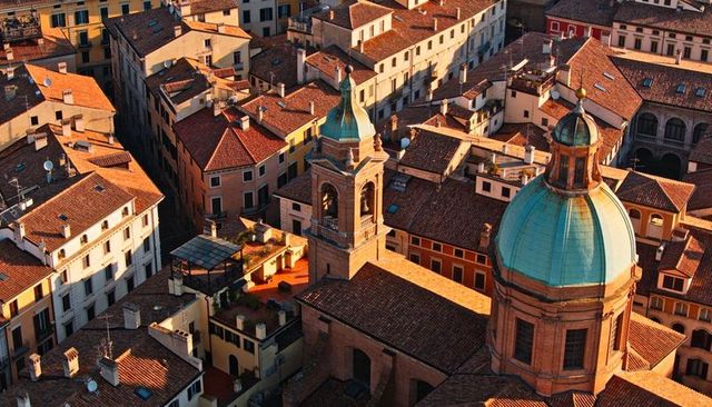 Copper dome and bell tower overlooking historic italian rooftops at warm sunset light
