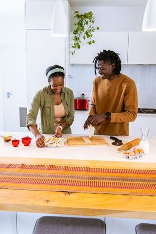 African american couple baking together in bright modern kitchen