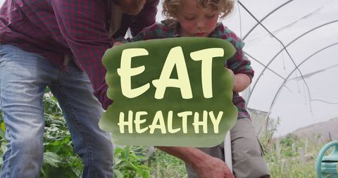 Father Teaching Son Gardening in Organic Greenhouse