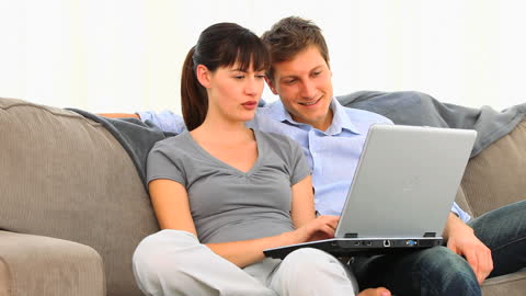 Happy Couple Relaxing on Couch with Laptop