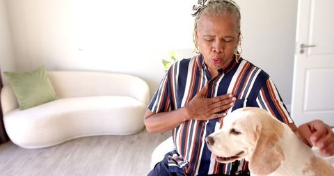 Joyful senior woman bonding with her dog at home