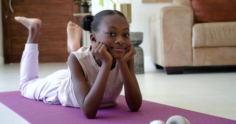 Preteen african american girl lying on yoga mat practicing exercise and relaxation at home