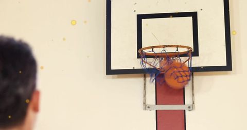 Basketball swishing through worn hoop with blue-red net in indoor gym action