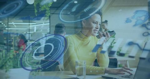 Woman in yellow turtleneck using smartphone and laptop in modern coworking space with AR data overla