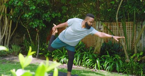 Man practicing yoga in lush backyard for complete outdoor relaxation