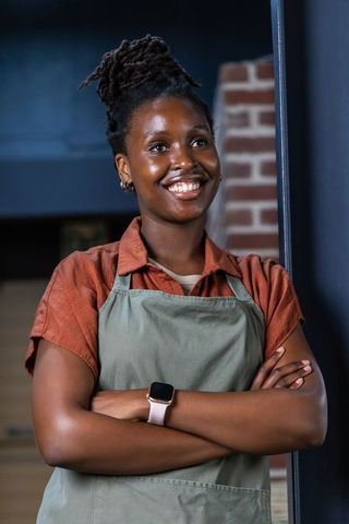 Confident african american barista standing with arms crossed wearing apron and smartwatch