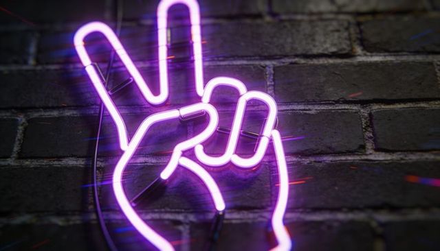 Glowing neon peace hand sign purple magenta tubing on dark brick wall retro nightlife vibe