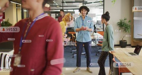 Young team collaborating in modern open office with smartphone and social notifications
