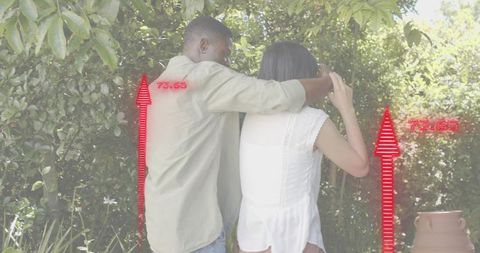 Couple walking and embracing on sunlit garden path with red digital overlay graphics