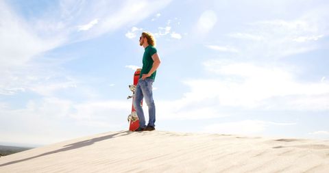 Adventurous Man With Snowboard on Sunny Dune Landscape