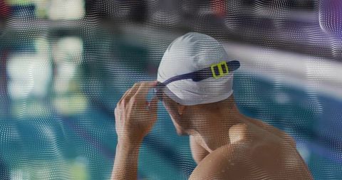 Male swimmer adjusting white swim cap and goggles strap at poolside preparing for training