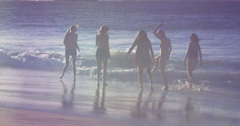 Group of Friends Enjoying Ocean Waves on Summer Beach