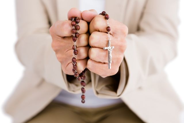 Close-up of a woman holding rosary beads, symbolizing faith and devotion. Ideal for use in religious publications, spiritual blogs, and articles about prayer and faith.