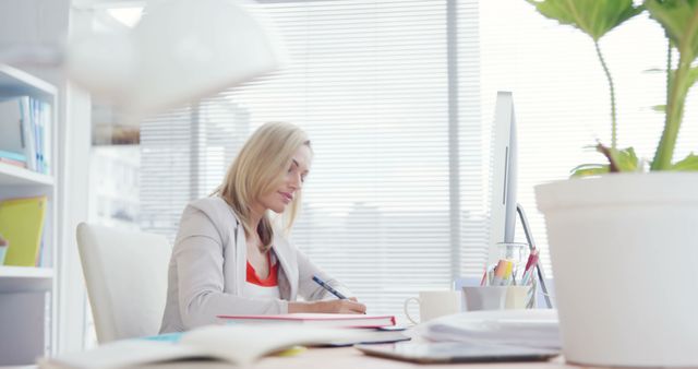 Focused Businesswoman Working at Desk in Bright Office - Download Free Stock Images Pikwizard.com