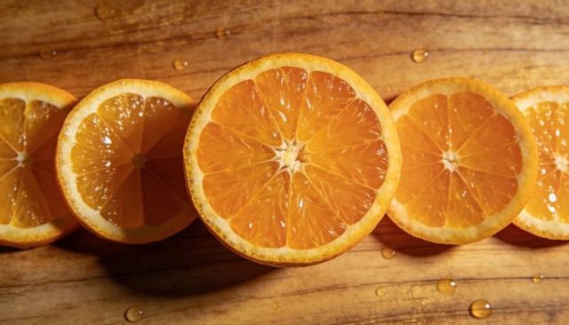Halved oranges glowing on wooden board with fresh juice droplets and radiant segments