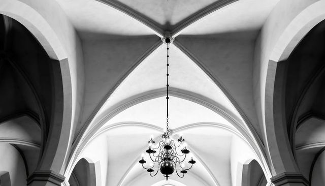 Gothic cathedral interior with ornate chandelier and symmetrical ribbed vaults