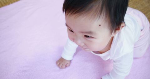 Asian Baby Crawling on Pink Blanket Indoors