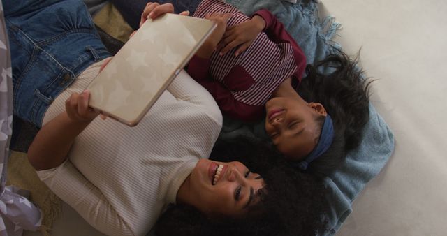 Image of happy african american mother and daughter using tablet together. Family, spending time together concept.