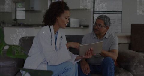 Nurse reviewing health data with senior patient at home using tablet
