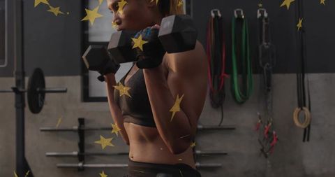 Midlife athlete pressing hex dumbbells in sports bra and leggings with gold star overlay