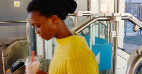Woman Entering Turnstile Holding Milkshake