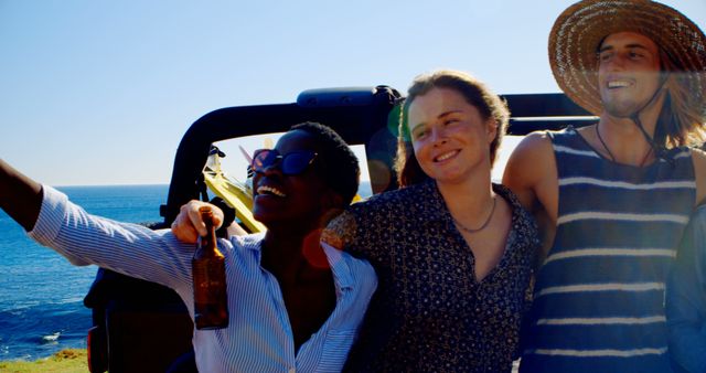 Three friends are celebrating and relaxing by the ocean during a sunny road trip. This image can be used in travel blogs, holiday promotions, vacation packages advertisements, lifestyle articles highlighting friendship and leisure activities.